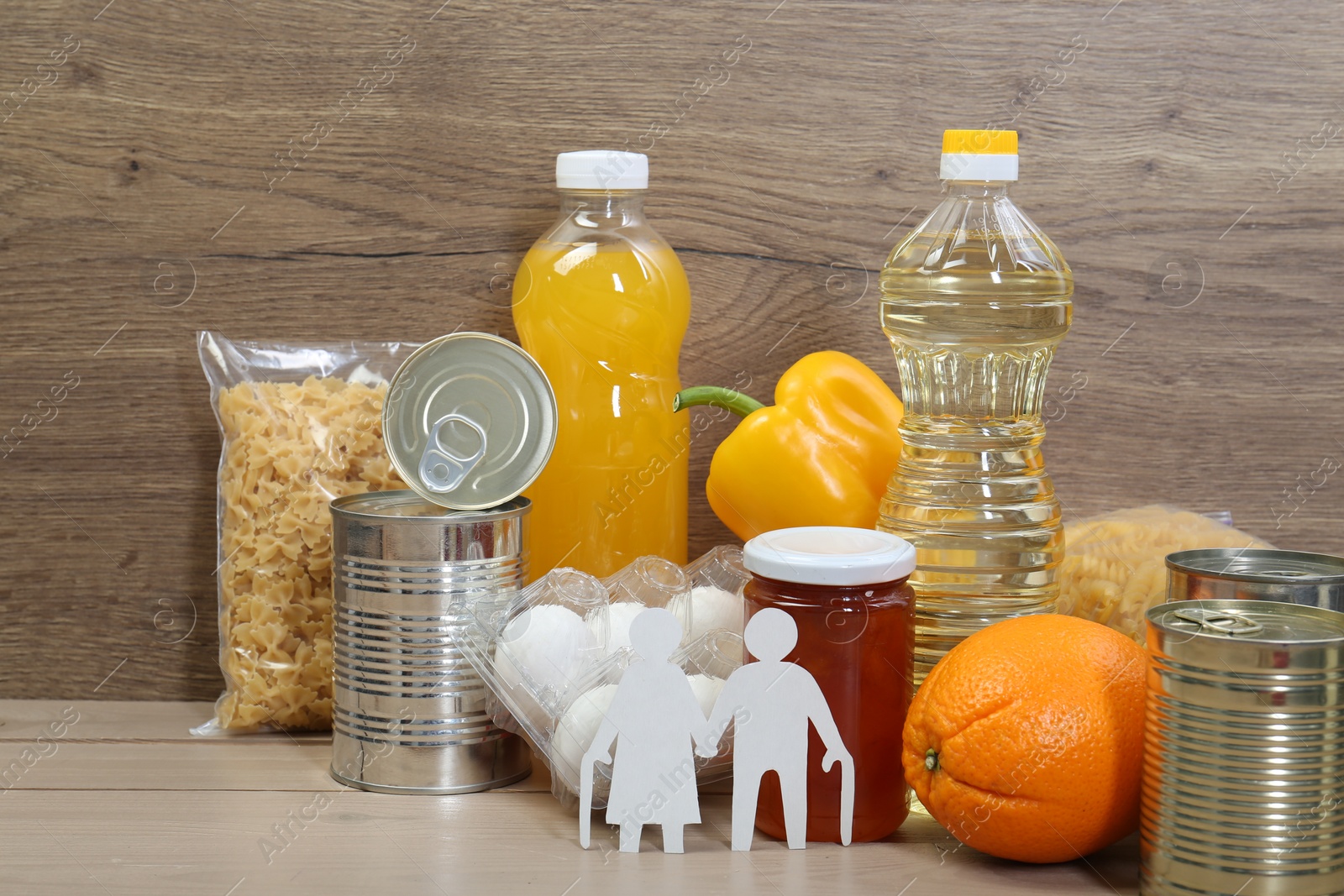 Photo of Humanitarian aid for elderly people. Different donation food and figures of senior couple on wooden table