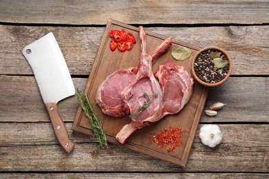 Fresh tomahawk beef cuts, butcher knife and spices on wooden table, top view