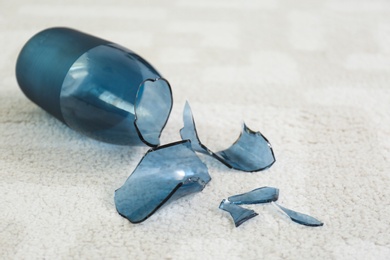 Photo of Broken blue glass vase on carpet, closeup