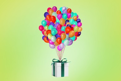 Many balloons tied to gift box on yellowish green background