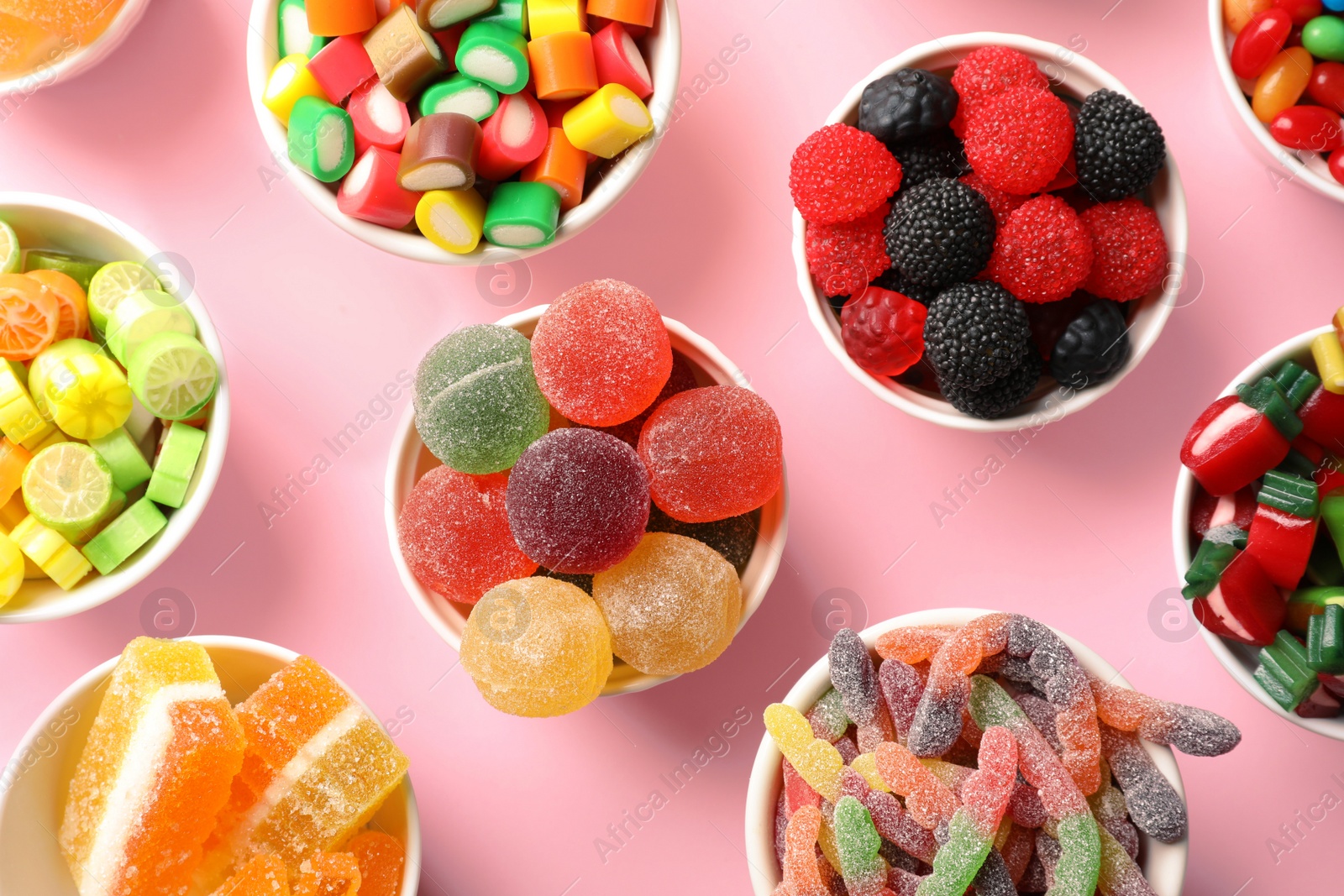 Photo of Flat lay composition with bowls of delicious colorful candies on color background