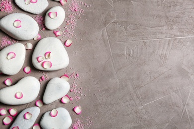 Flat lay composition with spa stones and flower petals on grey background. Space for text