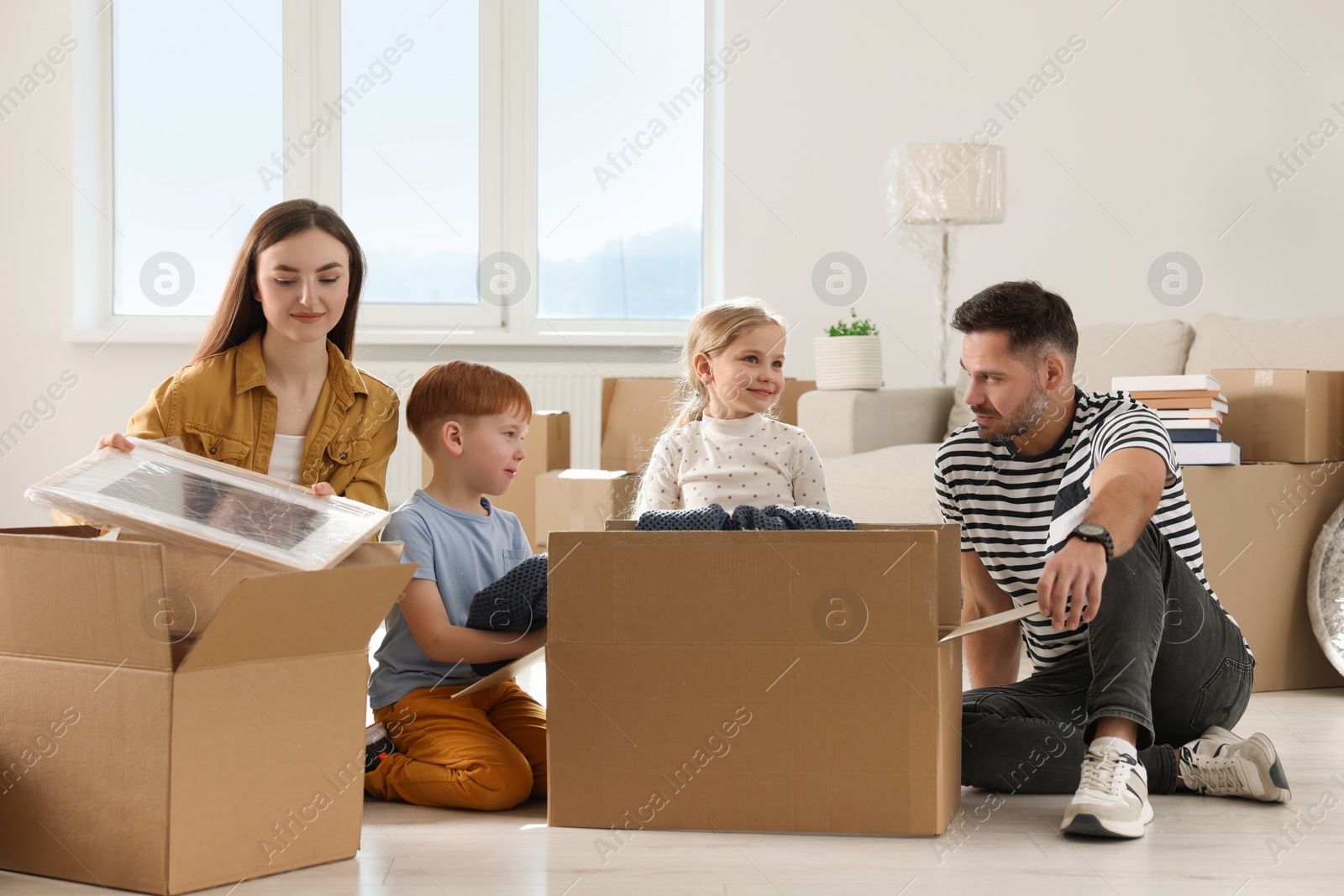 Photo of Happy family unpacking boxes in new apartment. Moving day