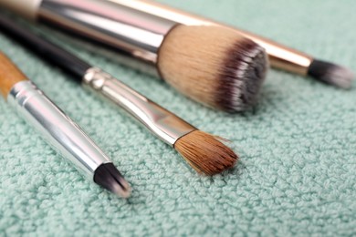 Photo of Clean makeup brushes on fluffy towel, closeup