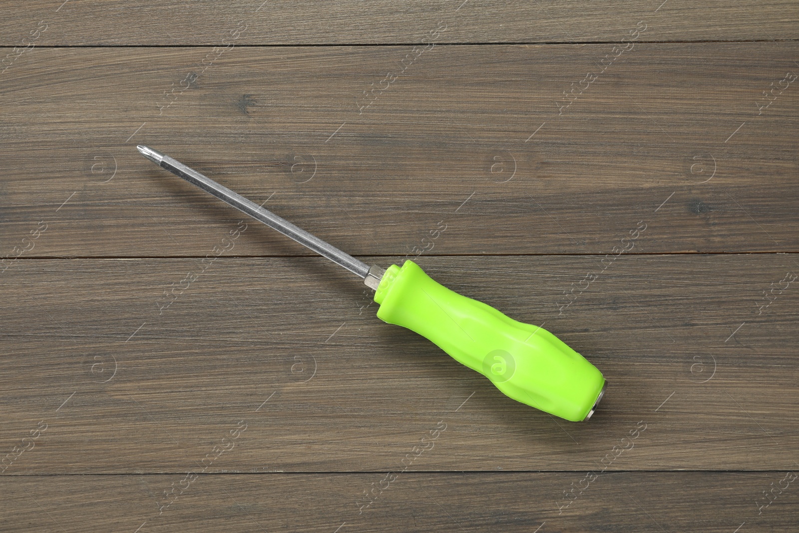 Photo of Screwdriver with green handle on wooden table, top view