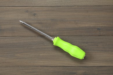 Photo of Screwdriver with green handle on wooden table, top view