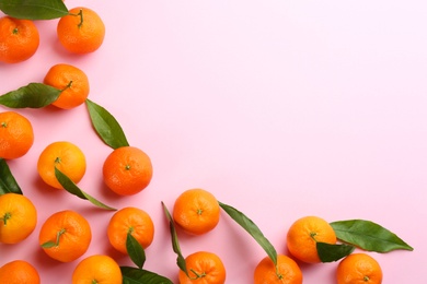 Photo of Fresh ripe tangerines with green leaves on pink background, flat lay. Space for text