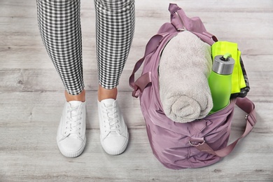 Photo of Young woman and sports bag with gym equipment, closeup. Ready for sport training