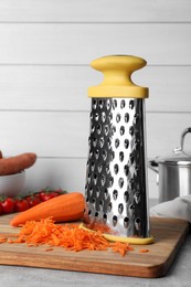 Grater and fresh ripe carrot on table