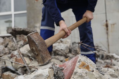 Man breaking stones with sledgehammer outdoors, selective focus