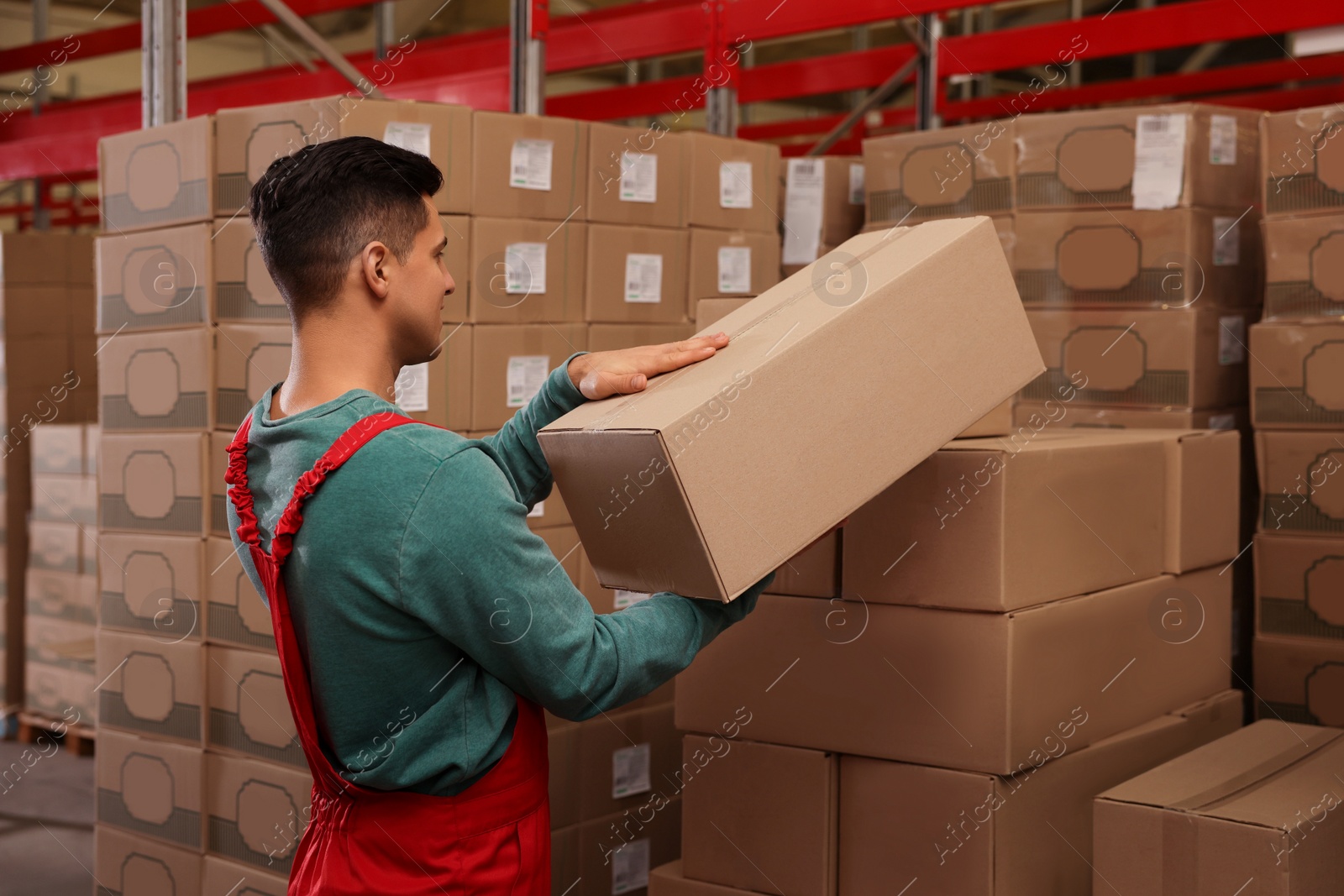 Photo of Worker stacking cardboard boxes in warehouse. Wholesaling