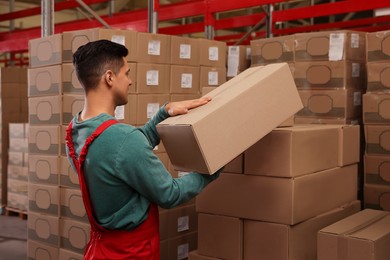 Worker stacking cardboard boxes in warehouse. Wholesaling