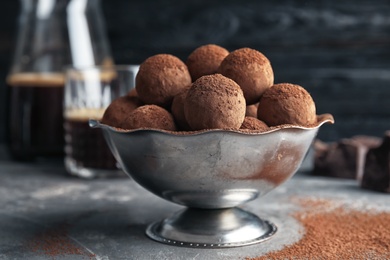 Photo of Bowl with tasty chocolate truffles on grey table