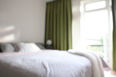 Photo of Blurred view of large bed near window in room