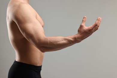 Man with muscular body on light grey background, closeup