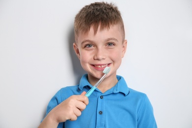 Photo of Portrait of little boy with toothbrush on light background