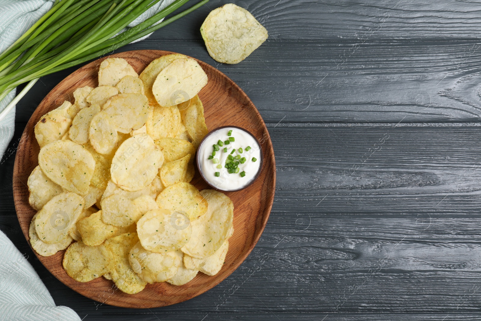 Photo of Chips with sour cream dressing on grey wooden table, flat lay. Space for text