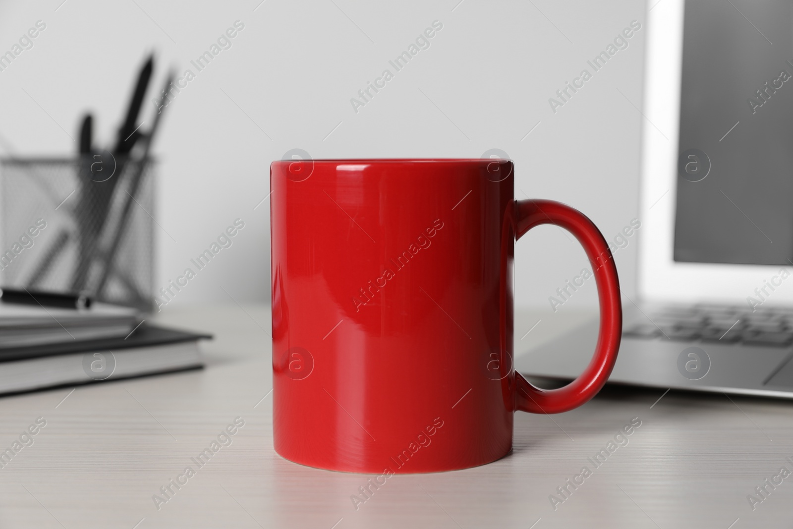 Red ceramic mug, laptop and stationery on white table at workspace Photo of Red ceramic mug, laptop and stationery on white table at workspace