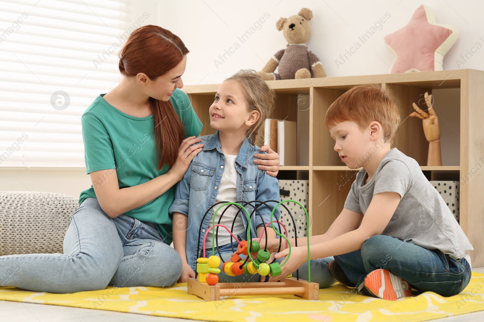 Photo of Happy mother and children playing with bead maze on floor in room. Learning mathematics with fun