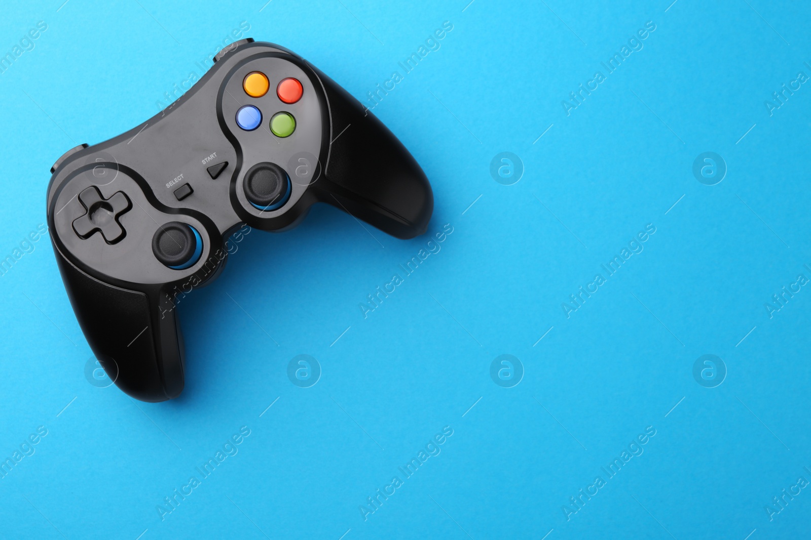 Photo of Wireless game controller on light blue background, top view. Space for text