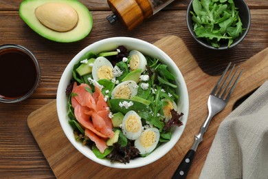 Delicious salad with boiled eggs, salmon and cheese served on wooden table, flat lay