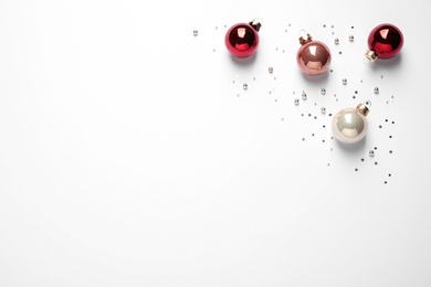 Colorful Christmas balls and sparkles on white background, top view. Space for text