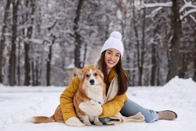 Woman with adorable Pembroke Welsh Corgi dog in snowy park