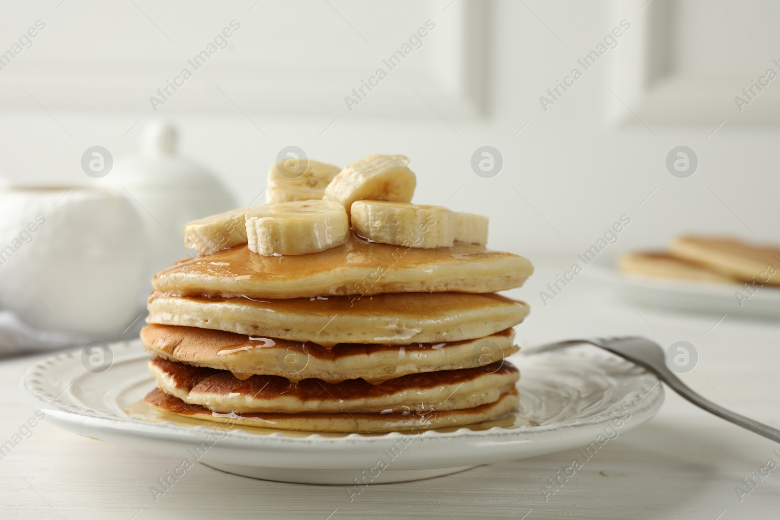 Photo of Delicious pancakes with bananas and honey on white wooden table, closeup