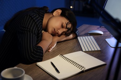 Photo of Tired overworked businesswoman napping at night in office