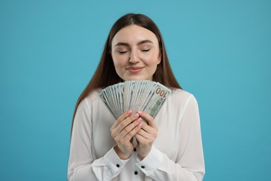 Smiling woman with dollar banknotes on light blue background