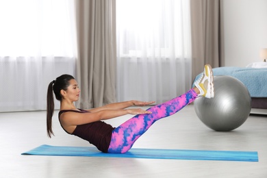 Young woman in fitness clothes doing exercise at home. Space for text