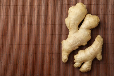 Fresh ginger on bamboo mat, top view. Space for text