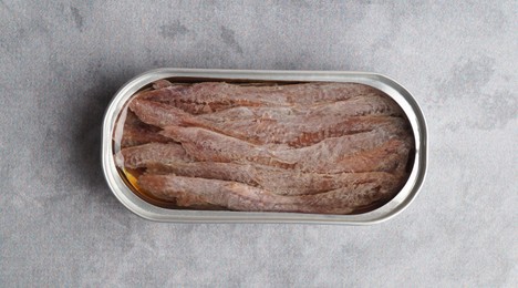 Canned anchovy fillets on light gray table, top view