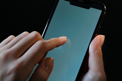 Photo of Woman using modern mobile phone on black background, closeup