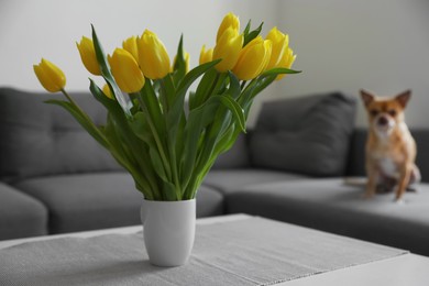 Photo of Bouquet of beautiful yellow tulips on table in living room