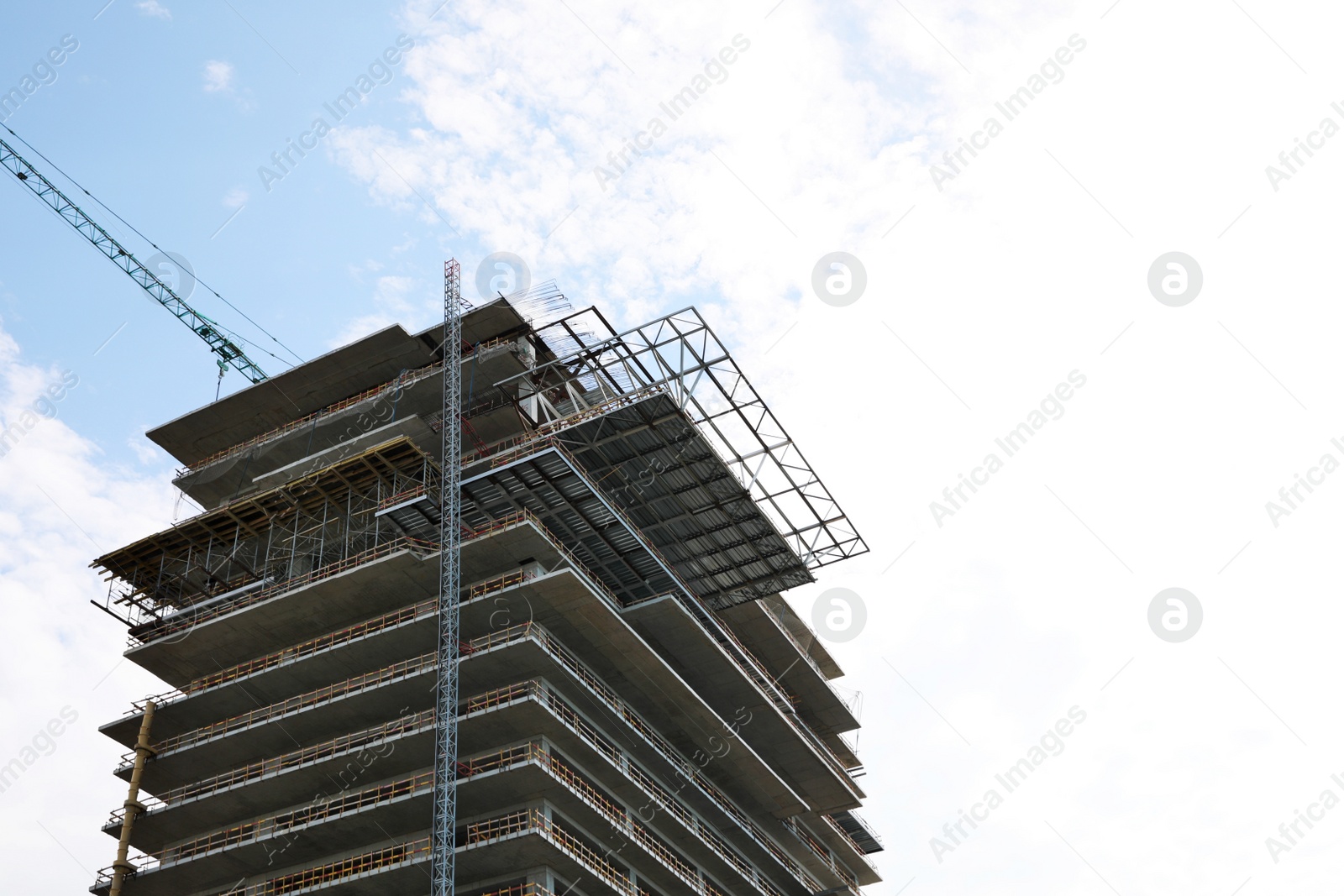 Photo of Multistory building under construction against cloudy sky, low angle view