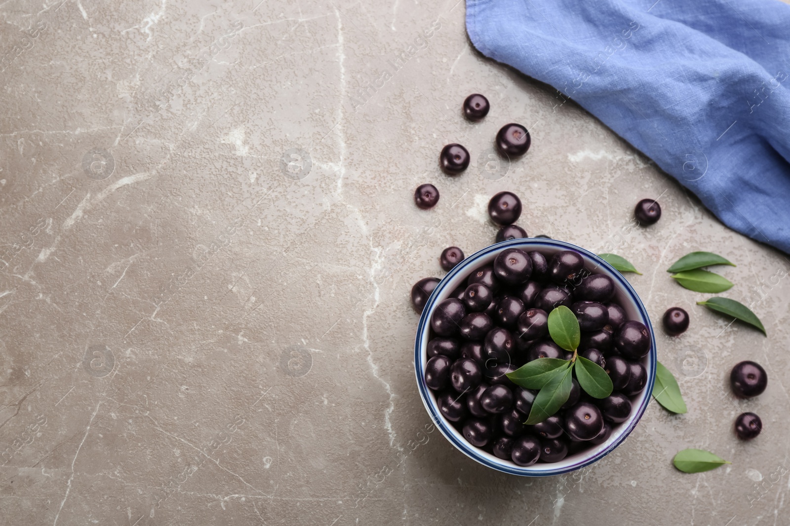 Photo of Fresh acai berries in bowl on light marble table, flat lay. Space for text