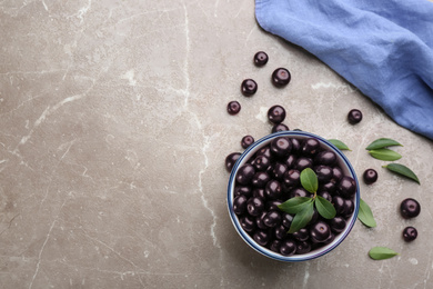 Photo of Fresh acai berries in bowl on light marble table, flat lay. Space for text