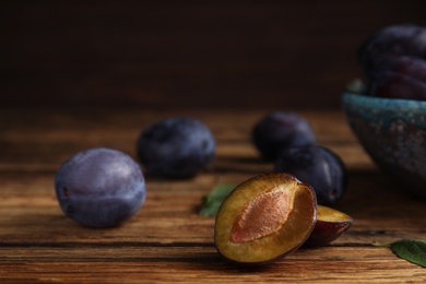 Delicious ripe plums on wooden table, closeup