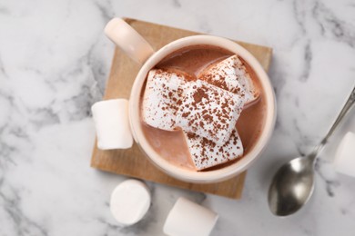 Photo of Cup of aromatic hot chocolate with marshmallows and cocoa powder served on white marble table, flat lay