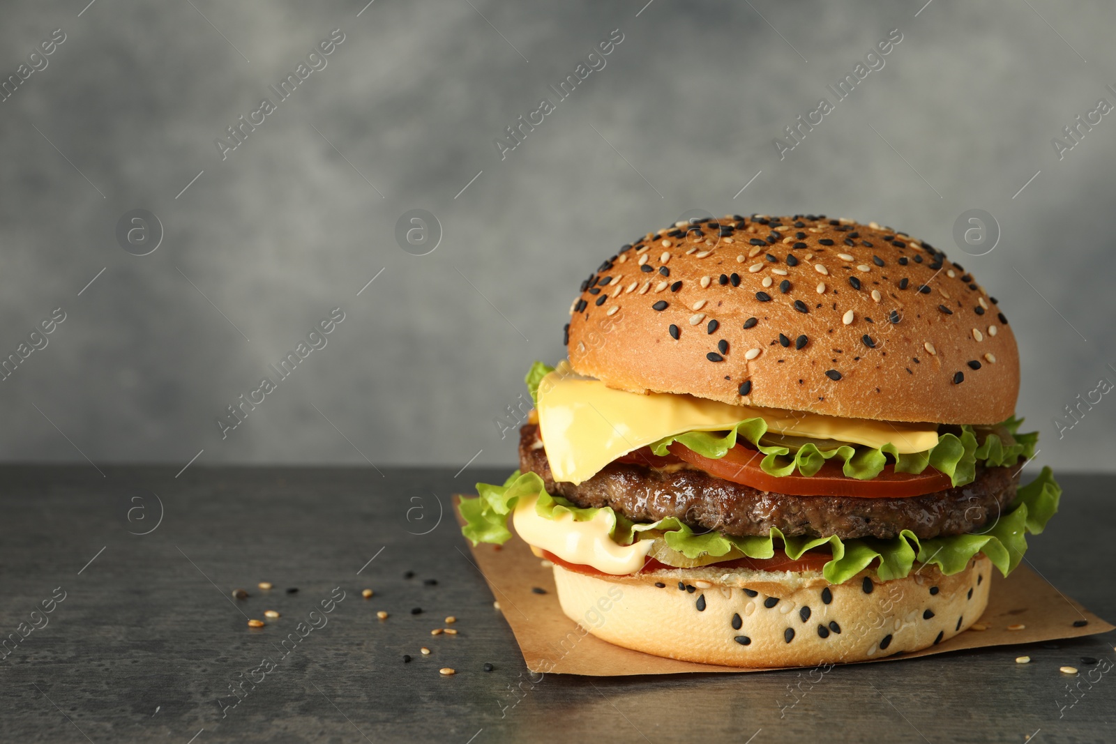 Burger with delicious patty on gray table, space for text Photo of Burger with delicious patty on gray table, space for text