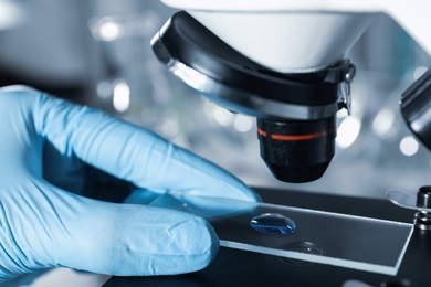 Doctor examining liquid sample with microscope, closeup. Laboratory analysis