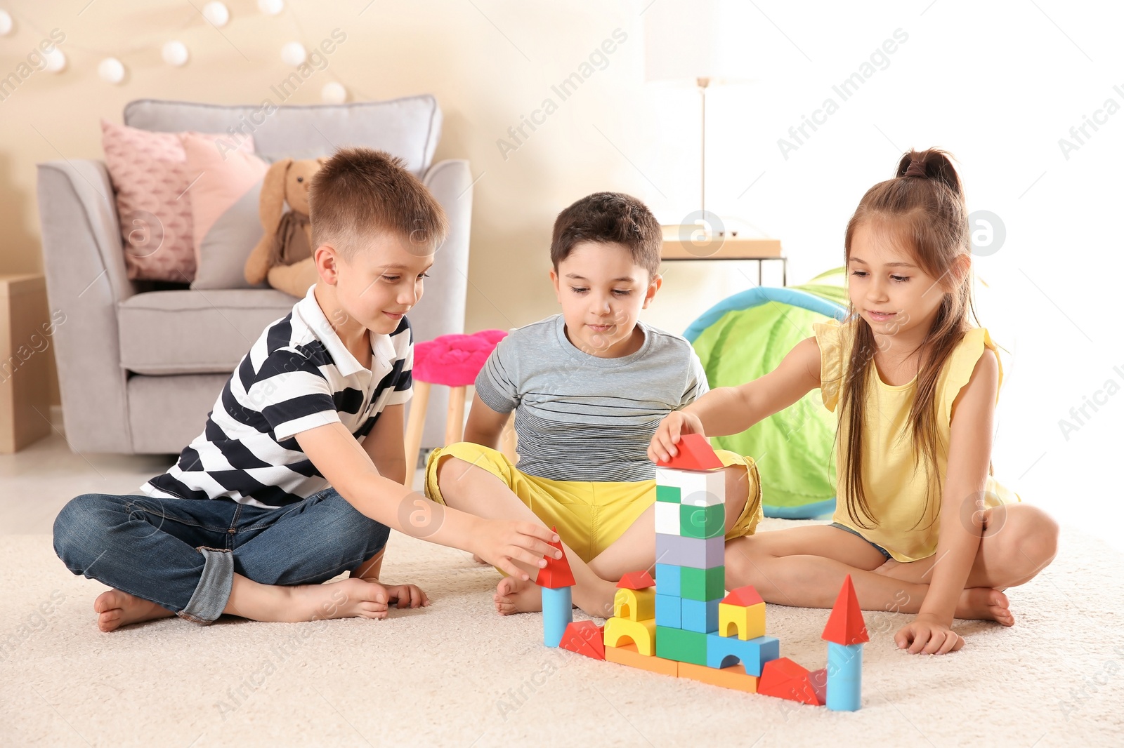 Photo of Cute little children playing with building blocks on floor, indoors
