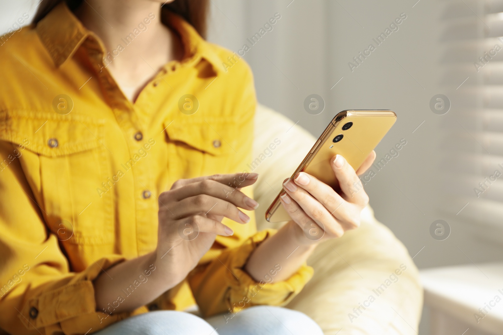 Photo of Young woman using modern smartphone indoors, closeup