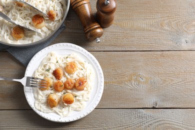Photo of Delicious scallop pasta served on wooden table, flat lay. Space for text