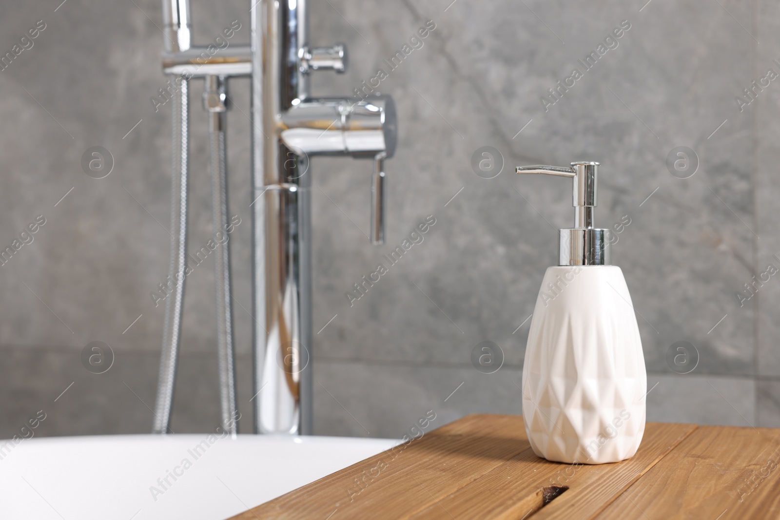 Photo of Bath accessory. Liquid soap dispenser on tub in bathroom, space for text