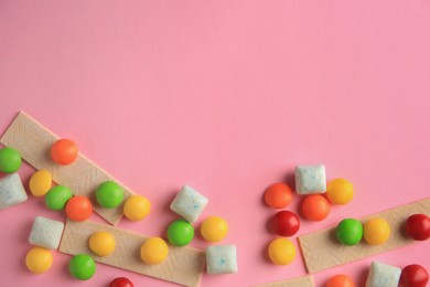 Photo of Different tasty chewing gums on pink background, flat lay. Space for text