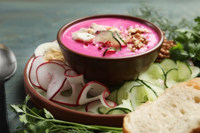 Photo of Delicious cold summer beet soup on blue wooden table, closeup