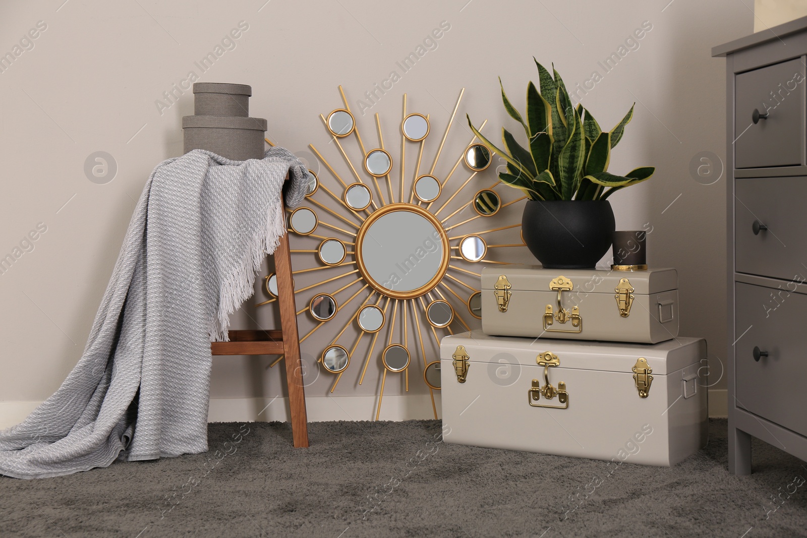 Photo of Stylish room interior with storage trunks, wooden stool and mirror