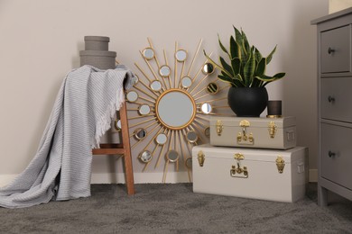 Stylish room interior with storage trunks, wooden stool and mirror